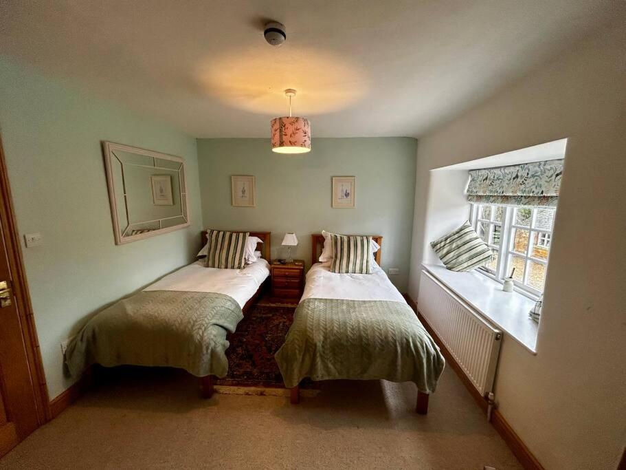 two beds in a small room with a window at Partridge in Lyddington