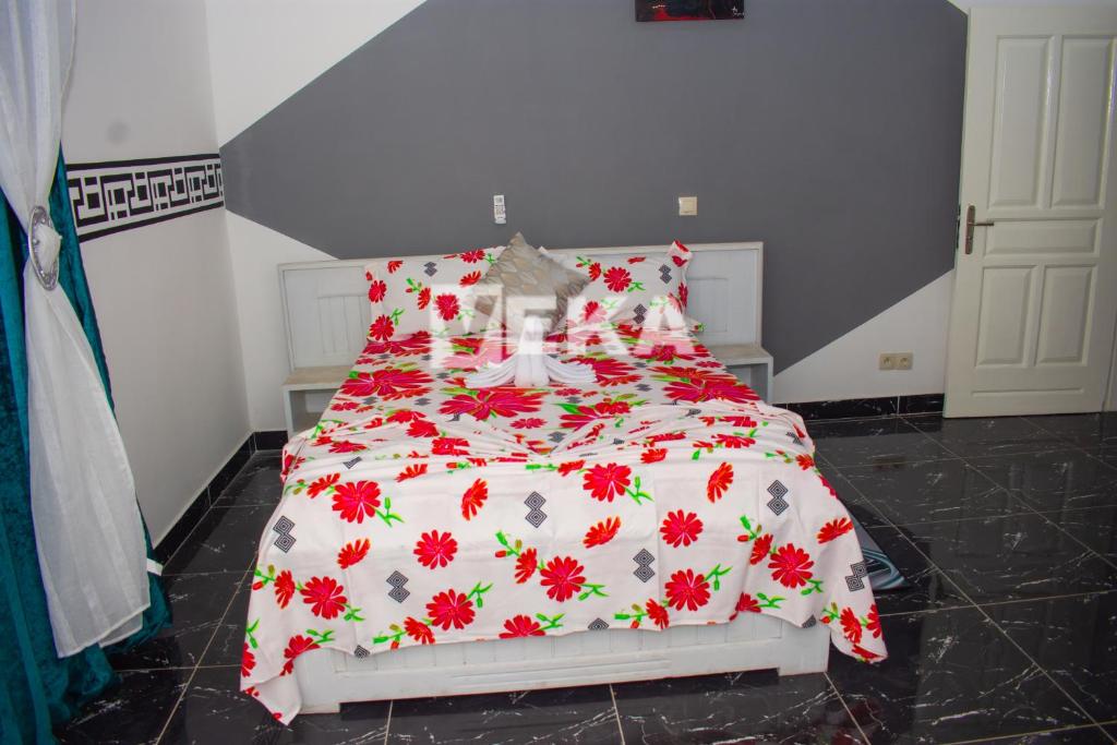 a bedroom with a bed with a red and white comforter at Appartement Chic in Pointe-Noire