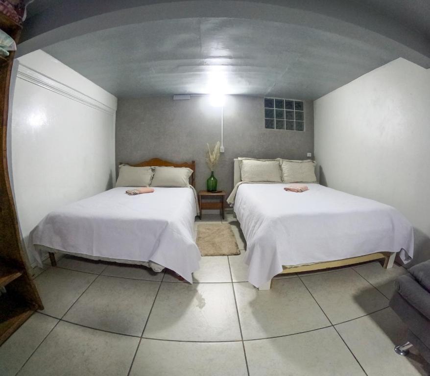 a room with two beds with white sheets at Hospedagem Recanto dos Viajantes in Bom Jardim da Serra