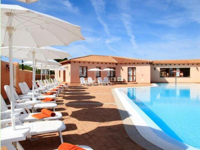 a pool with chairs and umbrellas next to a building at Apartment in Vignola Mare near Sandy Beach in Vignola Mare
