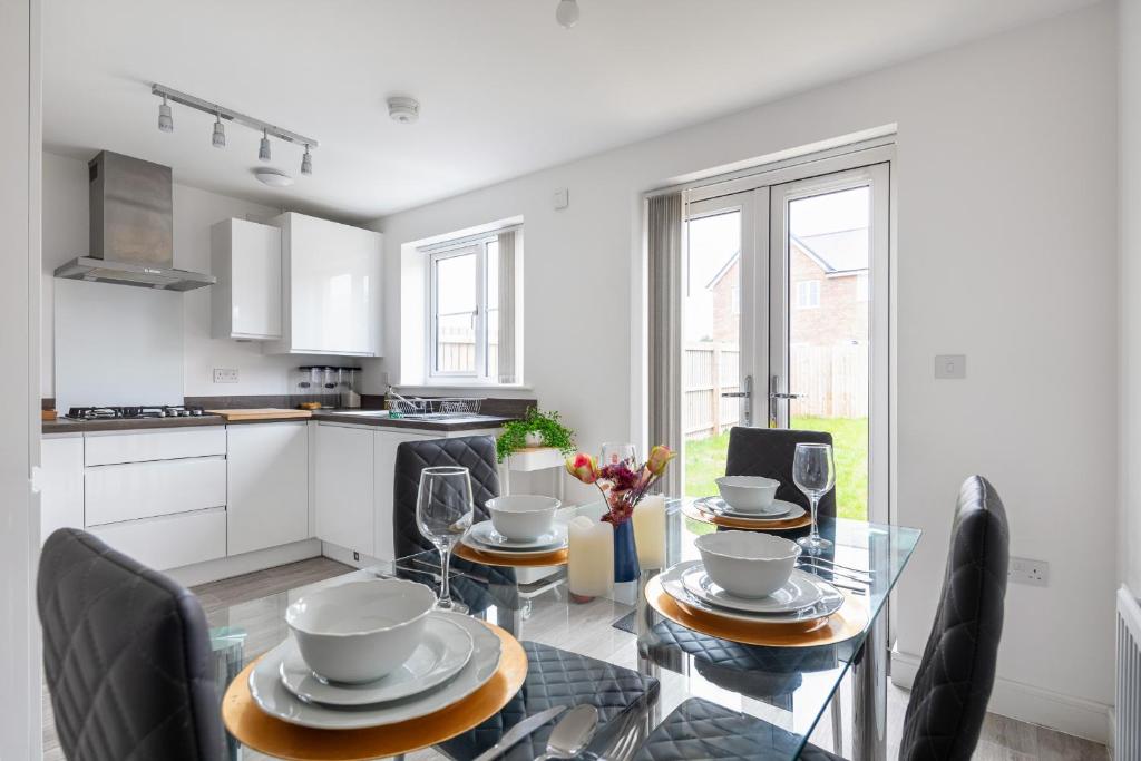 a kitchen and dining room with a glass table and chairs at NEW Luton 3 Bedroom house, Contractors & families, Sleeps 7 with Free Parking & WIFI in Luton