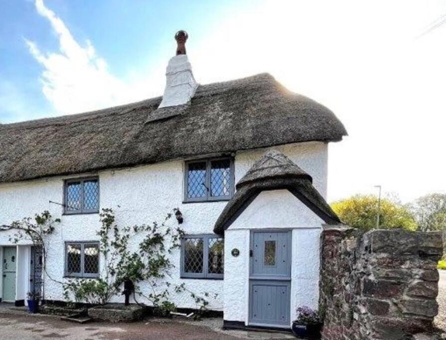an old white cottage with a thatched roof at Gorgeous Thatched Cottage in Torquay