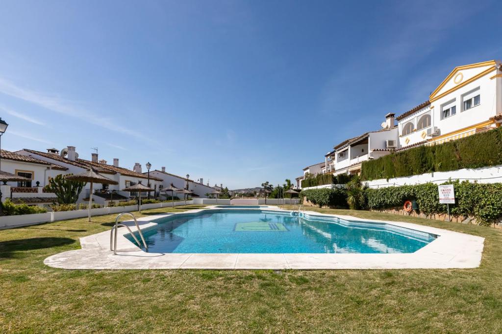 a swimming pool in the middle of a yard with houses at Casa Jardines del Sol J5 in Marbella
