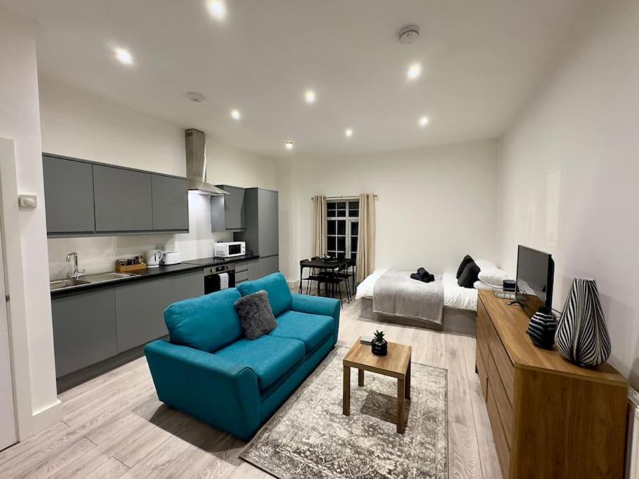 a living room with a blue couch and a kitchen at Hotel Studio Escape in Kent in Kent