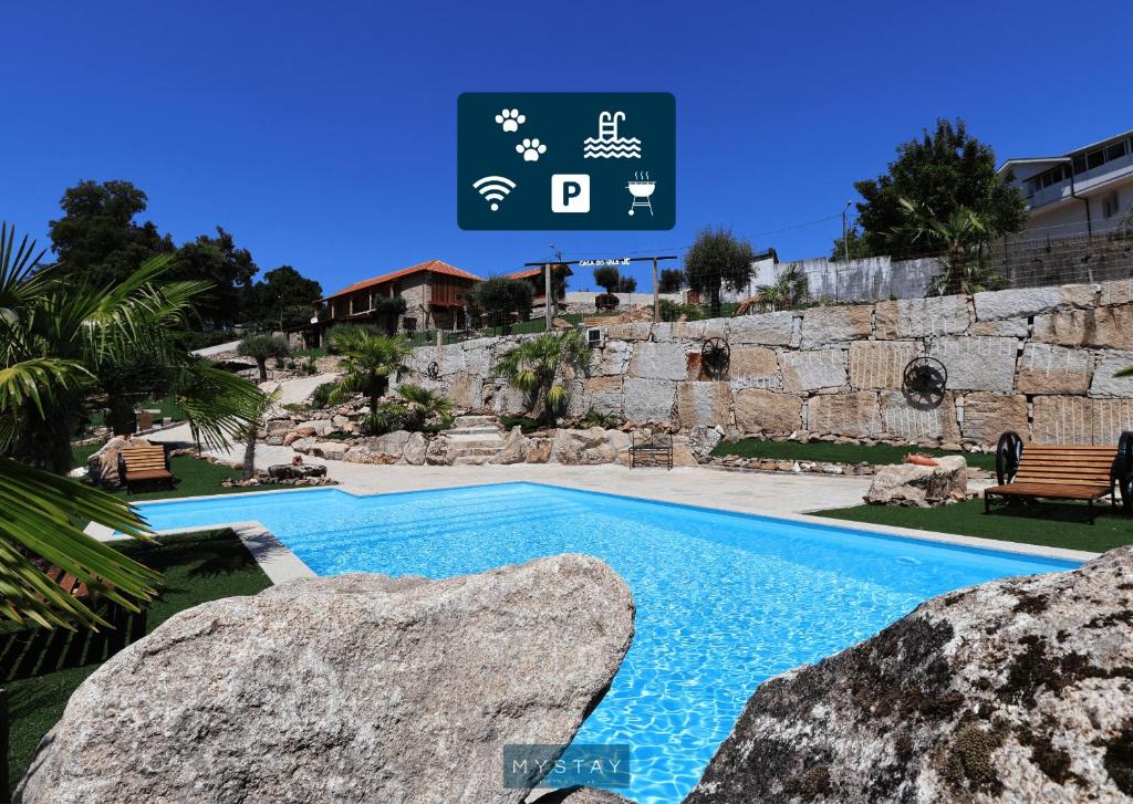 a swimming pool with two large rocks next to a building at MyStay - Casa do Vale JC in Vila Nune