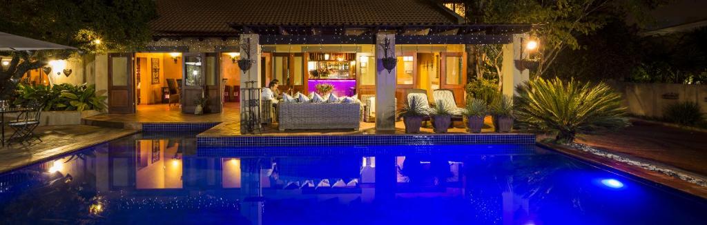 a swimming pool in front of a house at night at Opikopi Guest House in Pretoria