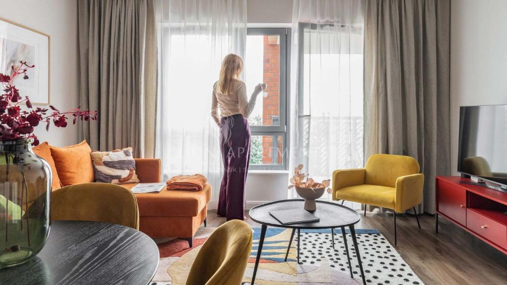 Una mujer parada en una habitación mirando por la ventana en Lion Apartments - SCALA City Center Apartments&Parking IB, en Gdansk