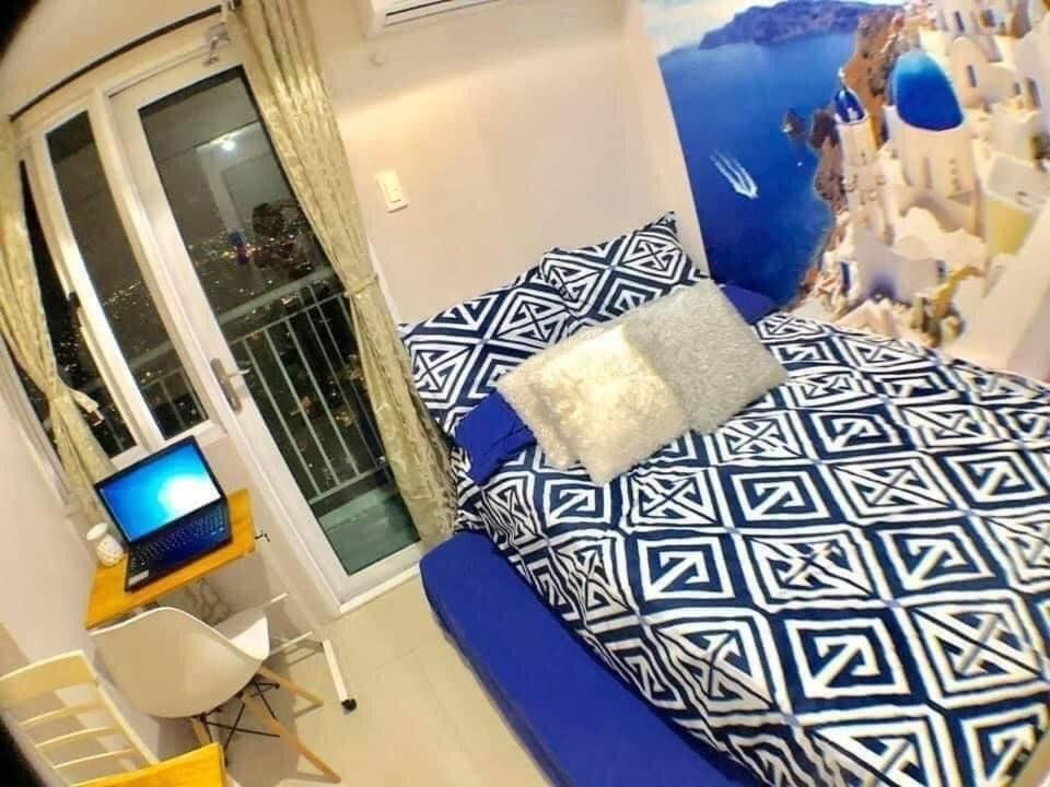 a bedroom with a bed and a desk with a laptop at The Grass Residences in Manila