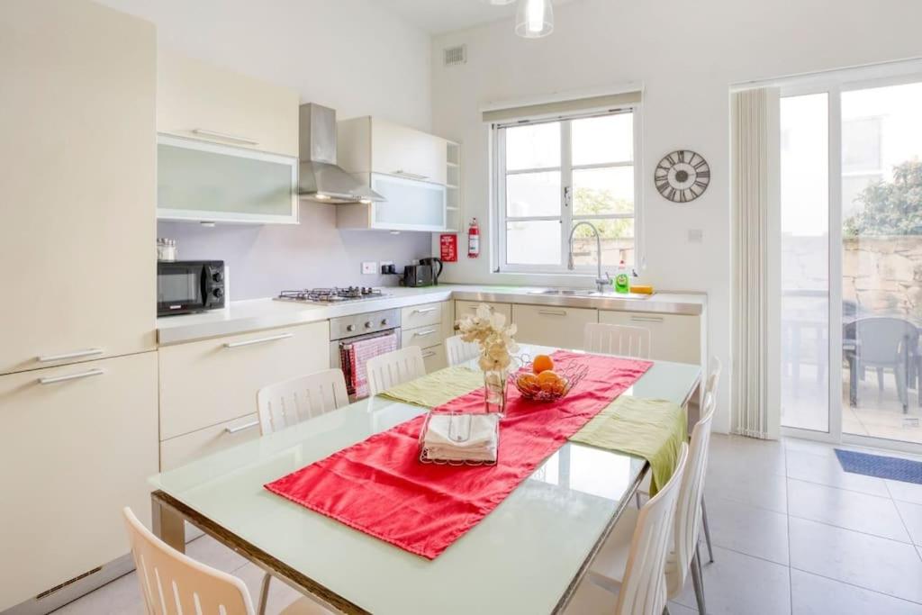 una cocina blanca con una mesa con un jarrón de flores. en Bright & Airy St. Julian's flat, en Il-Gżira