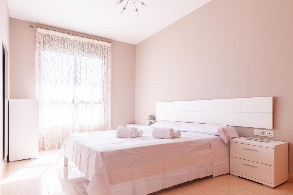 ein weißes Schlafzimmer mit einem großen Bett und einem Fenster in der Unterkunft Burriana Beach Retreat: Pool & Comfort in Burriana