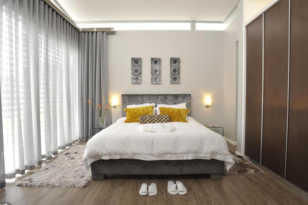 ein Schlafzimmer mit einem großen Bett mit gelben Kissen in der Unterkunft Serviced apartments in Eros in Windhoek