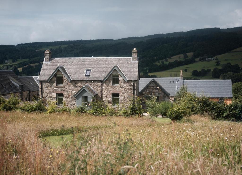 a large stone house in the middle of a field at Ballintaggart Farmhouse in Logierait