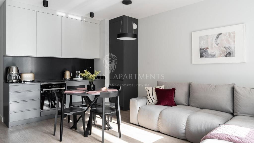 a kitchen and living room with a couch and a table at Lion Apartments - SCALA City Center Apartments&Parking IIB in Gdańsk
