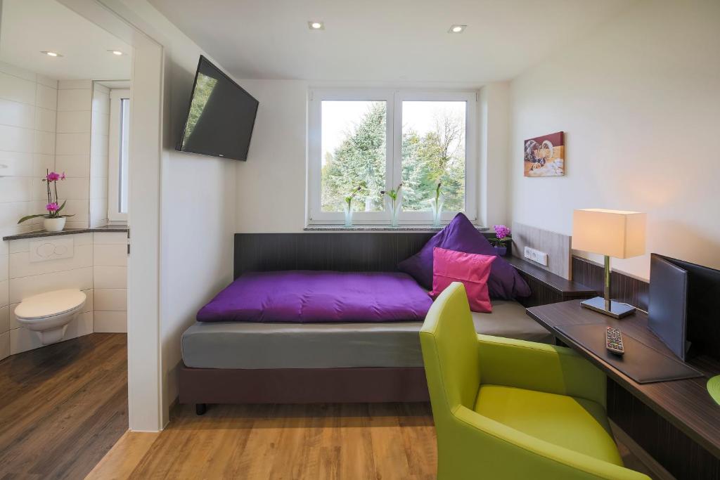 ein Wohnzimmer mit einem lila Sofa und einem Schreibtisch in der Unterkunft Hotel Gästehaus Stock Zimmer Schokotöpfle in Friedrichshafen