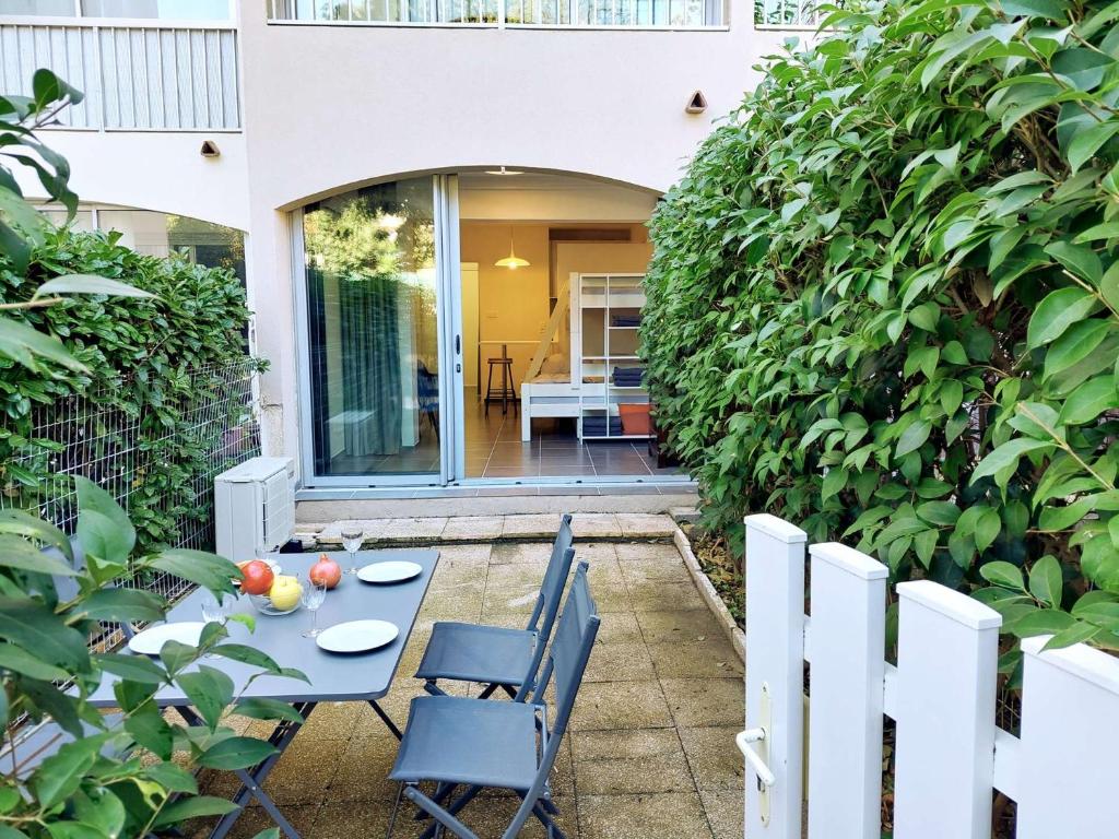 une terrasse avec une table et des chaises en face d'une haie dans l'établissement Jardin, terrasse, climatisation, à 5 minutes à pied des plages, commerces et animations, à Saint-Mandrier-sur-Mer