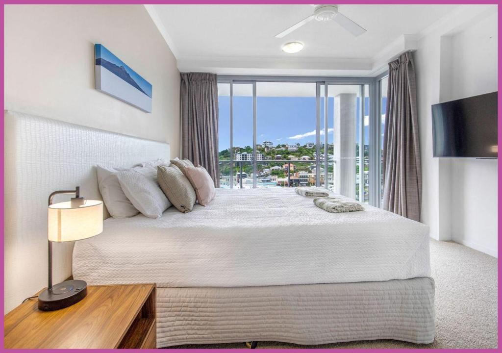 a bedroom with a large bed with a large window at Apartment 1102 | 11th Floor River & Stadium Views in Townsville