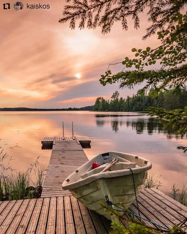 a boat sitting on a dock next to a lake at Beautiful and spacious lakeside cottages in Imatra