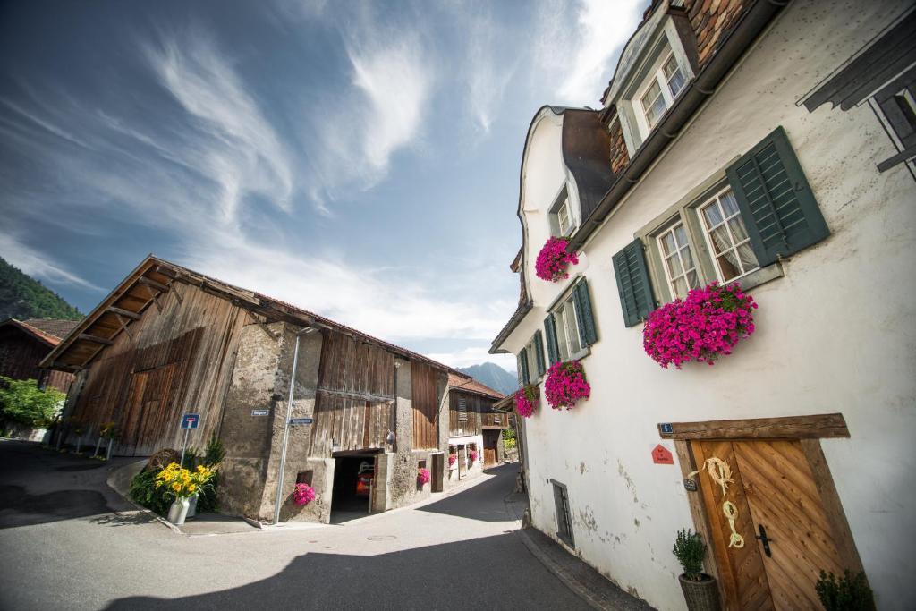 un vieux bâtiment avec des fleurs roses sur les fenêtres dans l'établissement Haus Meierhüsli, à Malans