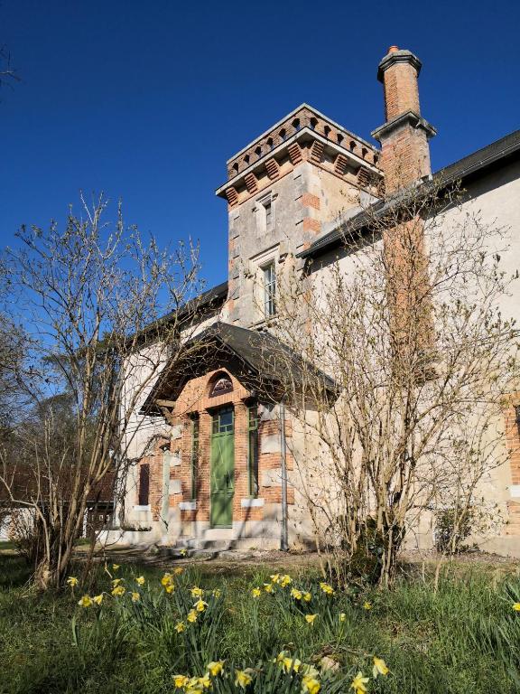 un ancien bâtiment en briques avec une cheminée et une porte verte dans l'établissement Domaine de l'Ile, à Boulleret