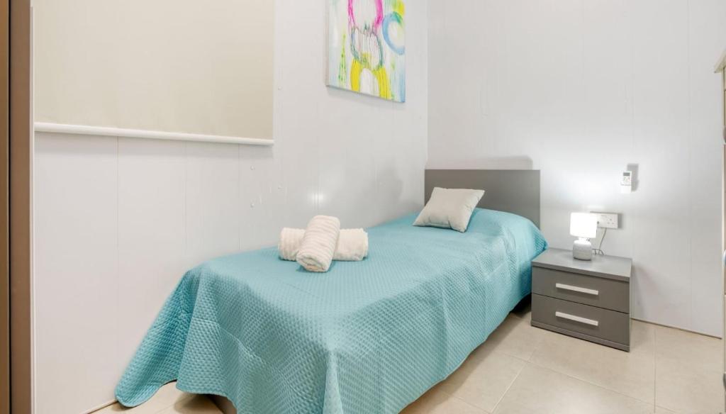 um quarto com uma cama com um cobertor azul em Cozy Room St Julian's em Il-Gżira
