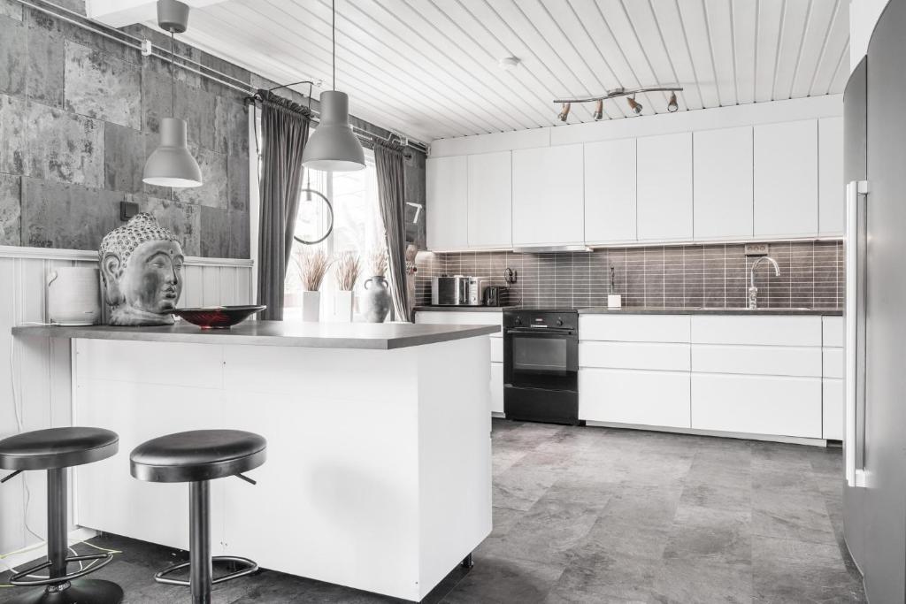 eine Küche mit weißen Schränken und Barhockern in der Unterkunft Guestly Homes - 4BR Cozy House near windfarm in Piteå