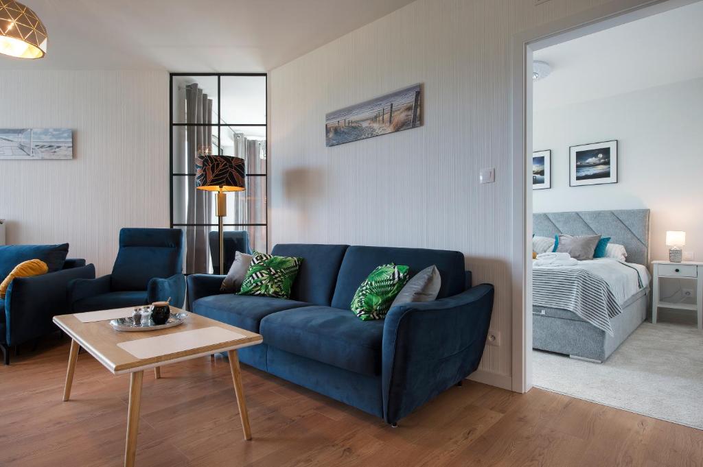 sala de estar con sofá azul y cama en Apartament Premium PINEA 523, en Pobierowo