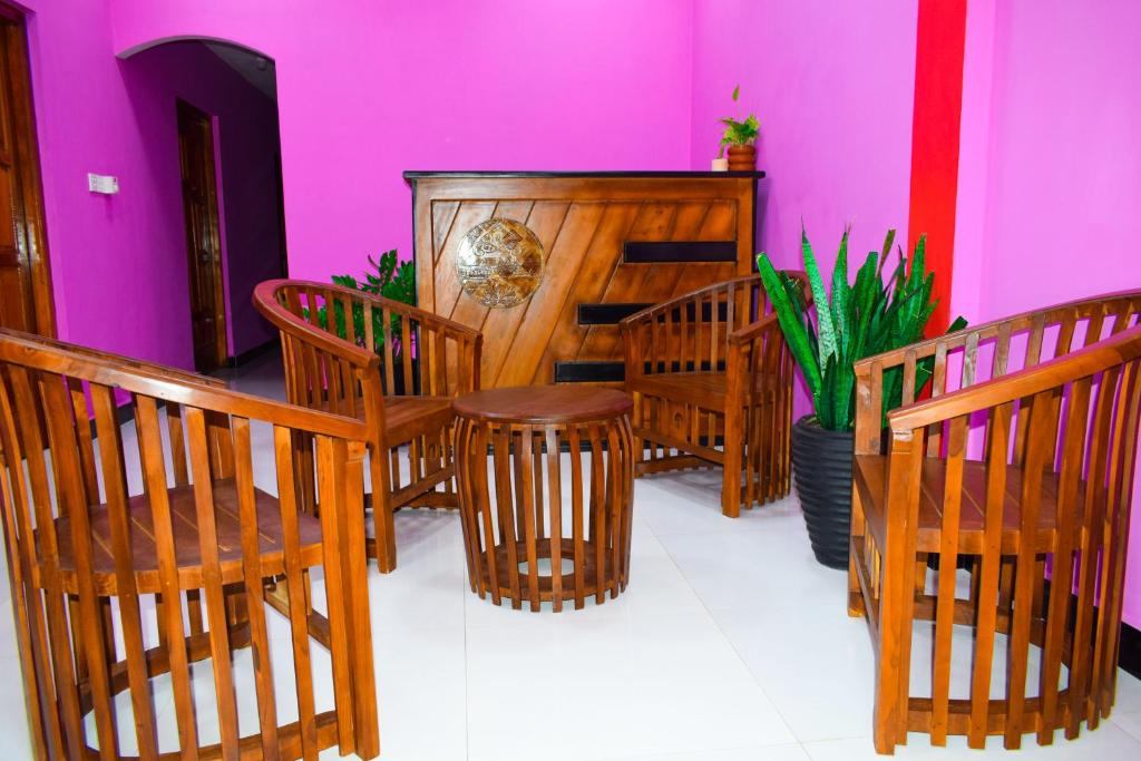 een kamer met houten stoelen en een podium met paarse muren bij Hema Holiday Villa in Trincomalee