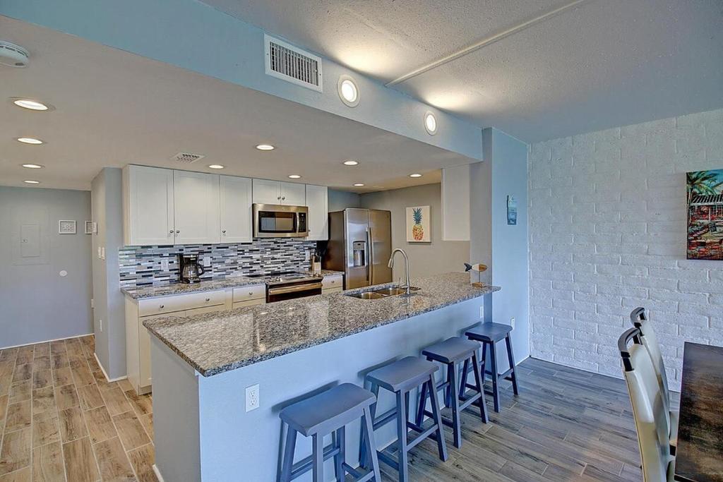 a kitchen with a large counter with blue stools at A Salty Day Getaway at Sea Sands Condominiums in Port Aransas