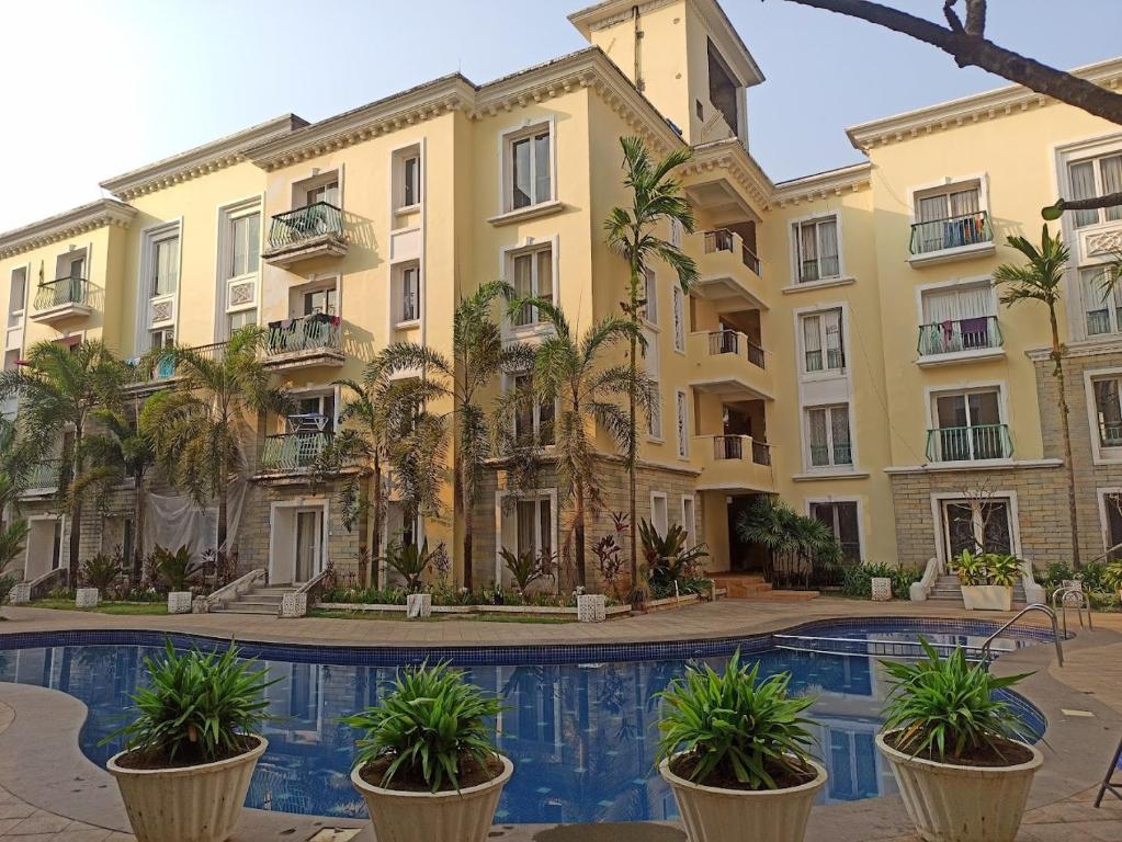 an apartment building with a swimming pool and palm trees at Asta by Avim in Goa