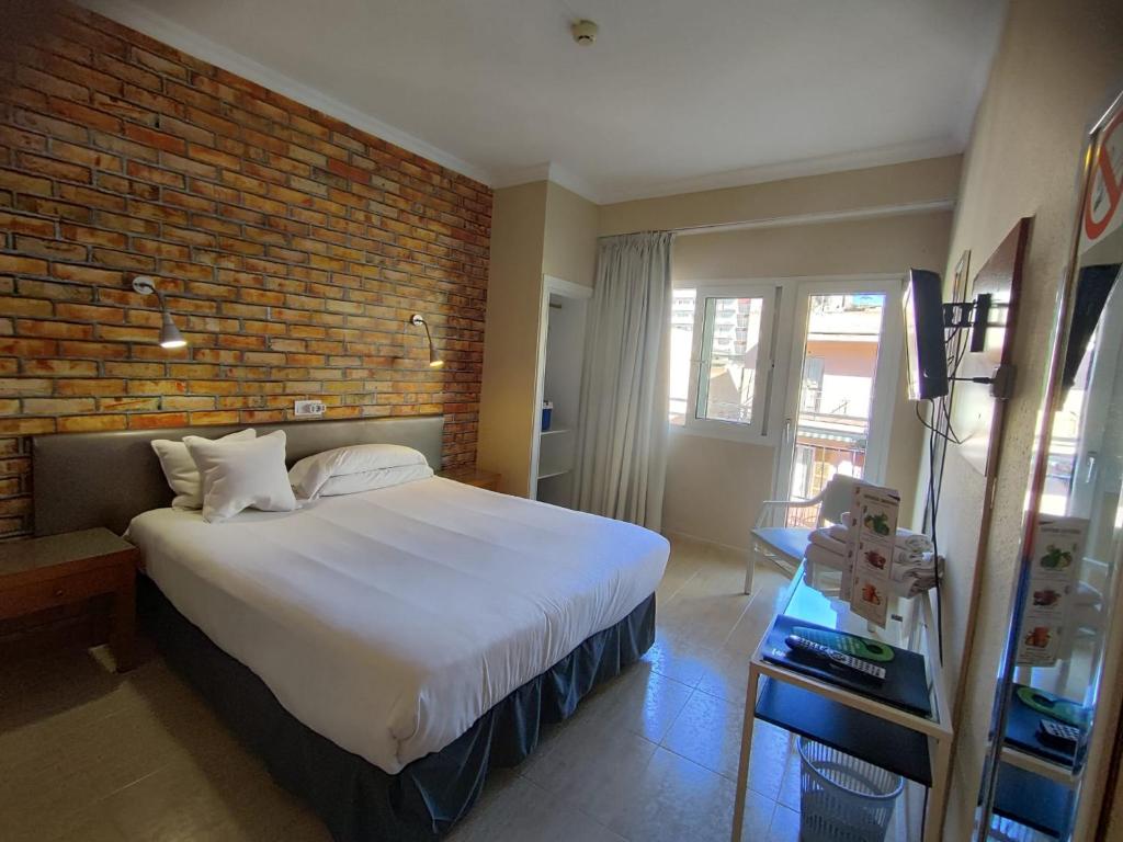 a bedroom with a large bed and a brick wall at Hostal Mar del Plata in El Arenal