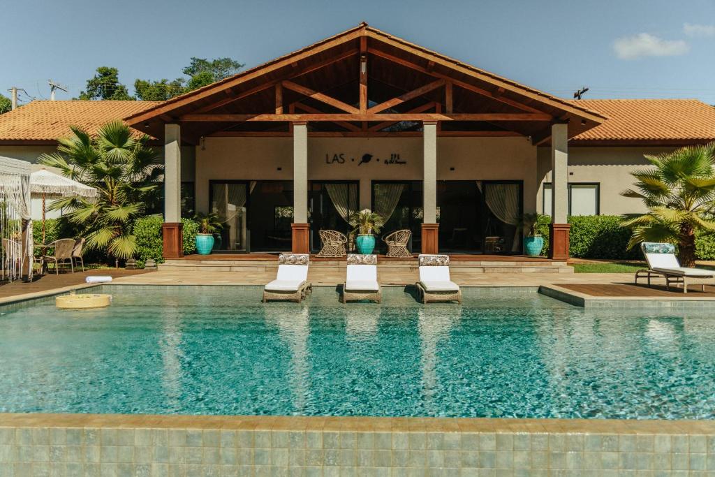 a swimming pool with chairs and a house at LAS HOTEL BOUTIQUE in Foz do Iguaçu