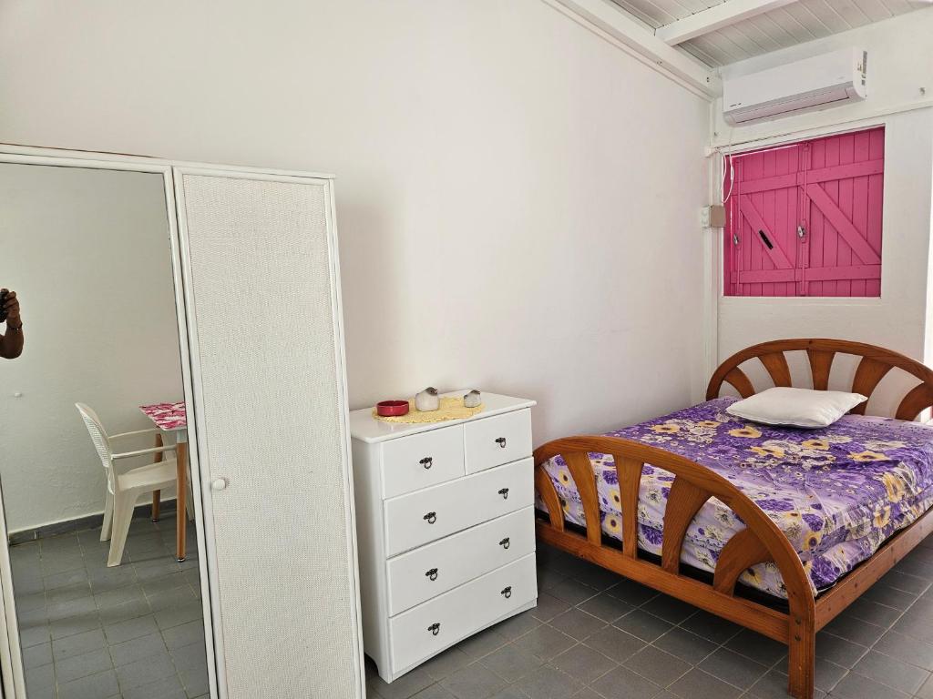 - une chambre avec un lit, une commode et une porte rouge dans l'établissement Au paradis créole, à Le Moule