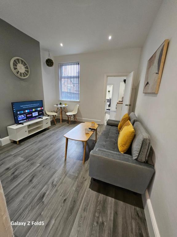 a living room with a couch and a tv at By the Joyous Stays in Stoke on Trent