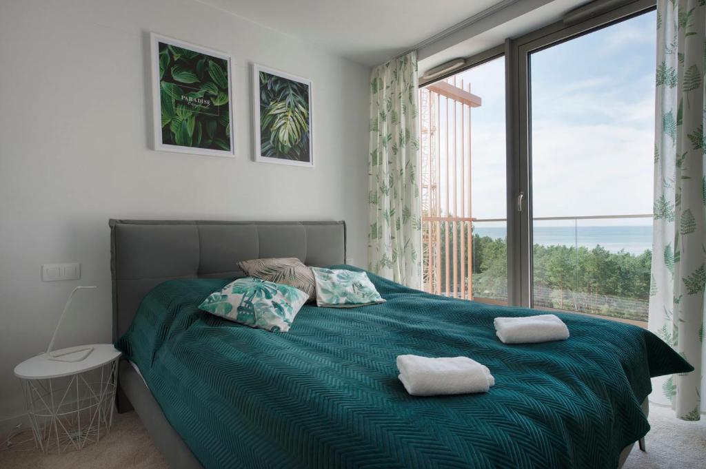 a bedroom with a bed with a large window at Apartament Premium Sea View PINEA 704 in Pobierowo