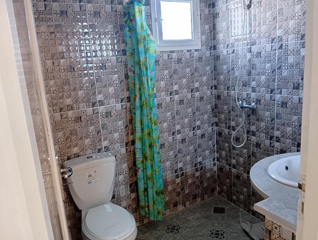 e bagno con servizi igienici e tenda per la doccia. di Bel appartement proche de la mer Hammamet a Hammamet