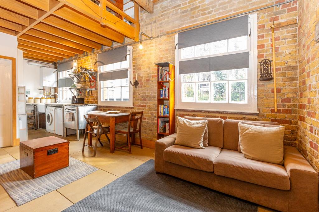 uma sala de estar com um sofá e uma parede de tijolos em Unique Detached House wPrivate Courtyard, London em Londres