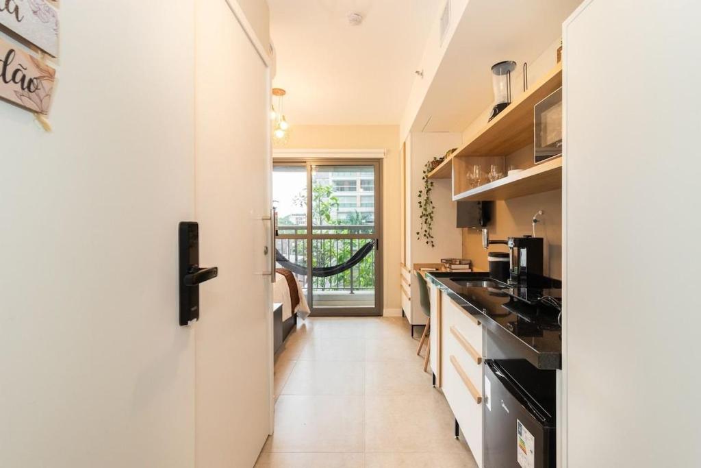 uma cozinha com paredes brancas e uma porta que leva a um quarto em Zainalofts7 Moema - 1km Ibira e 200m metrô 213 ID em São Paulo