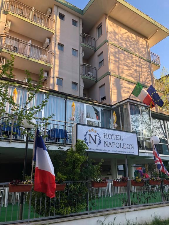 un panneau indiquant la marge de l'hôtel et des drapeaux devant un bâtiment dans l'établissement Hotel Napoleon, à Cesenatico