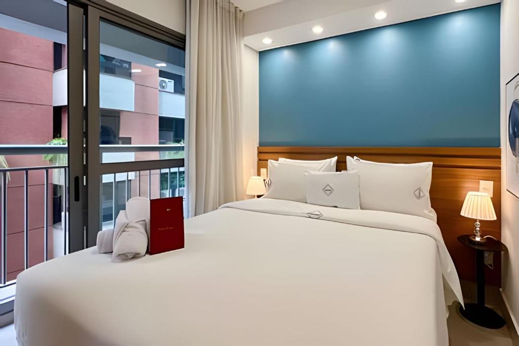 Un dormitorio con una gran cama blanca y una ventana en Zainalofts7 Moema - 1km Ibira e 200m metrô 509 ID, en São Paulo