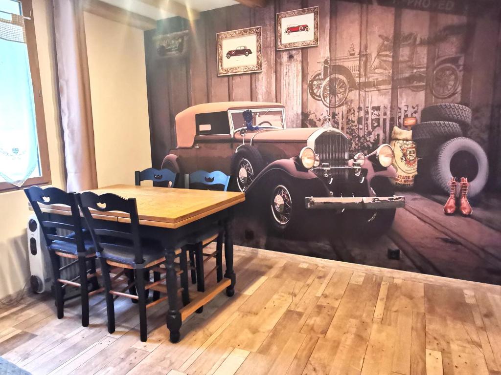 Le Vieux Tacot, stationnement gratuit في لو بوي: غرفة مع طاولة وسيارة قديمة على الحائط