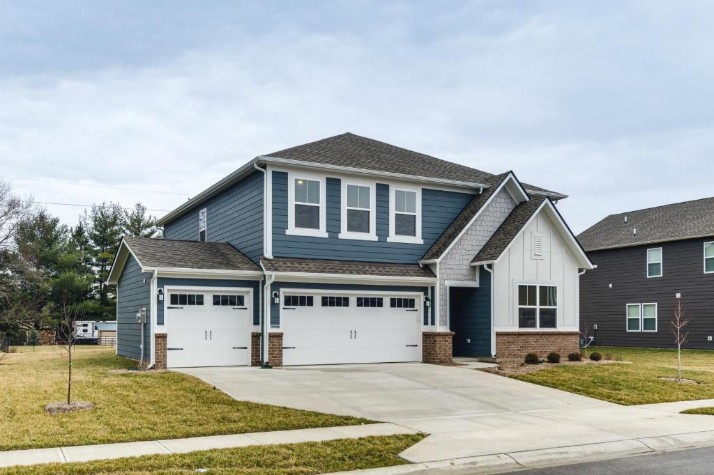 a blue house with two white garage doors at Quiet Avon Home - Near Indianapolis Speedway! in Avon