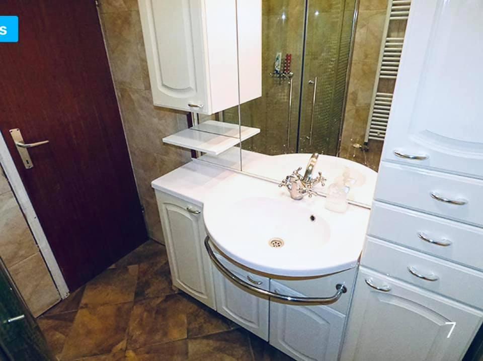 ein Badezimmer mit einem weißen Waschbecken und einem Spiegel in der Unterkunft Ardent Apartman in Siófok