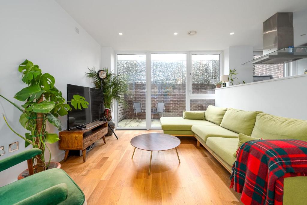 GuestReady - Modern lodge with garden في لندن: غرفة معيشة مع أريكة وطاولة