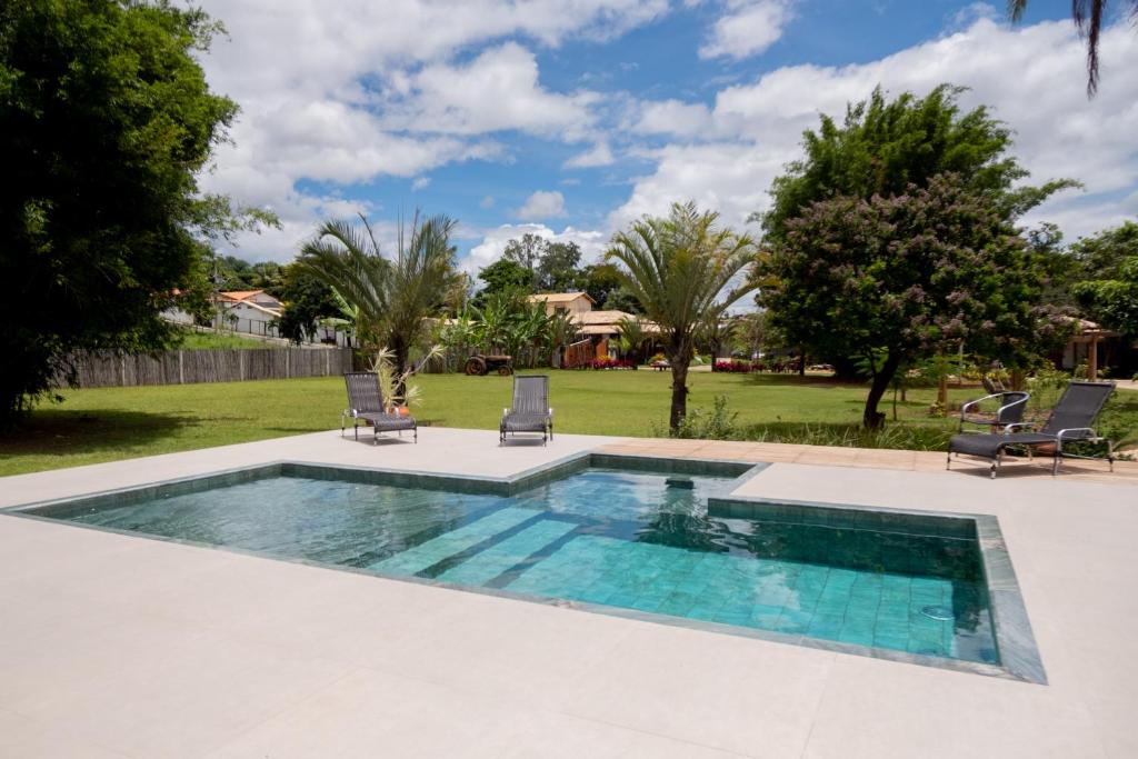 una piscina con 2 sillas y un patio en Pousada Rancho Soberbo, Serra do Cipó, en Santana do Riacho