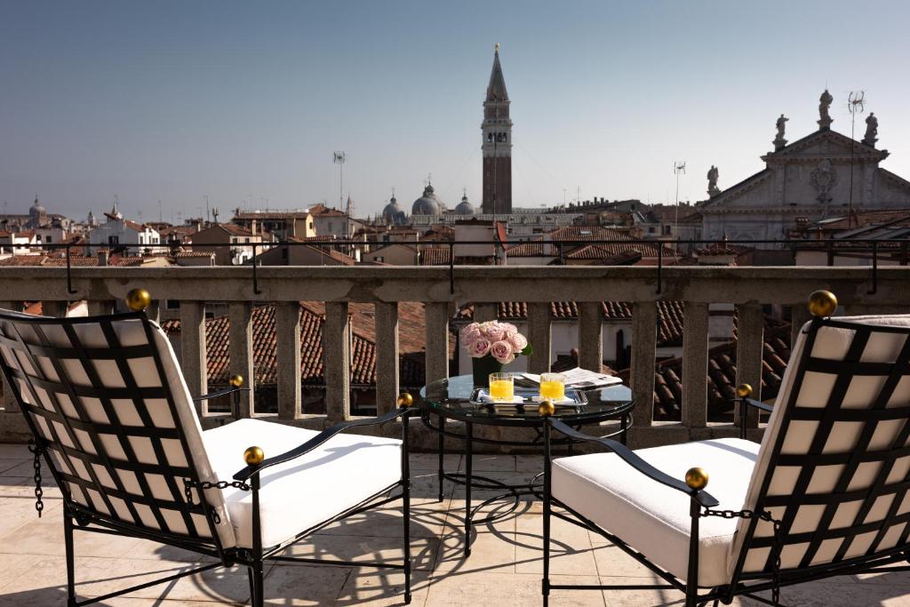 een tafel en stoelen op een balkon met uitzicht op de stad bij Nolinski Venezia - Evok Collection in Venetië