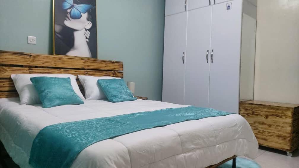 ein Schlafzimmer mit einem großen Bett mit blauen Kissen in der Unterkunft Vizuri Hideout in Kampala