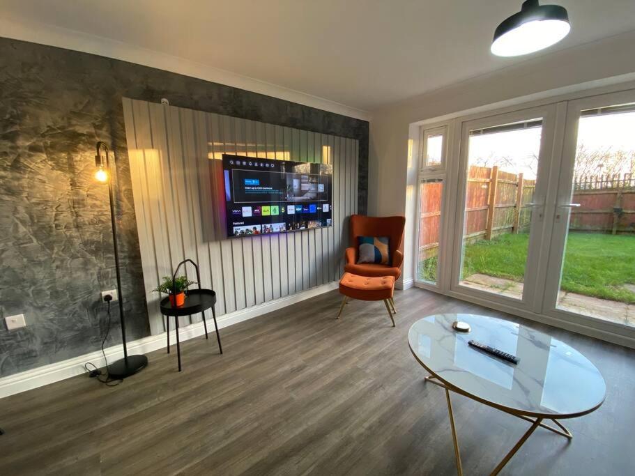 a living room with a glass table and a chair at Stylish 3-Bed House with Free Parking & Netflix by HP Accommodation in Northampton