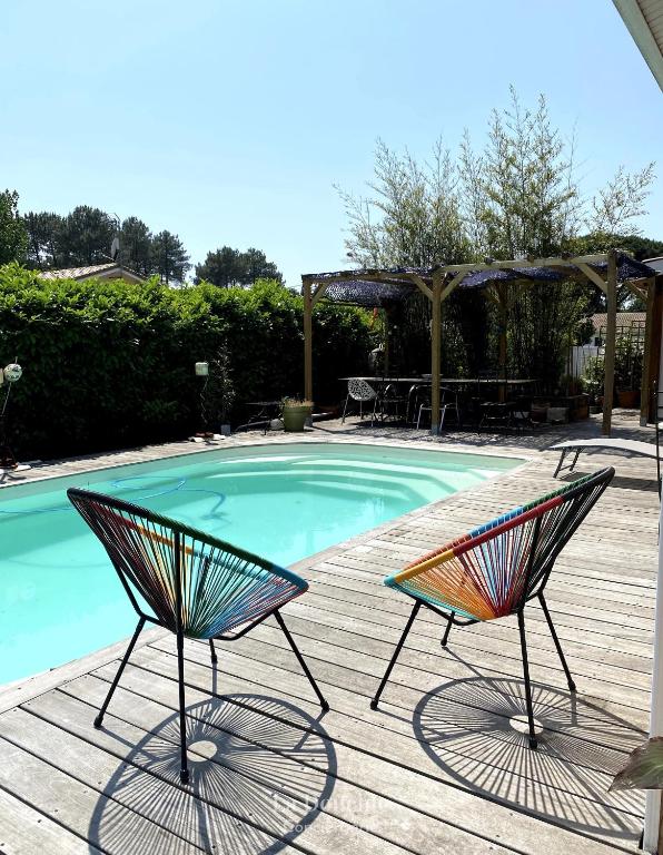 deux chaises assises à côté d'une piscine dans l'établissement Maison bois flotté, à Lège-Cap-Ferret