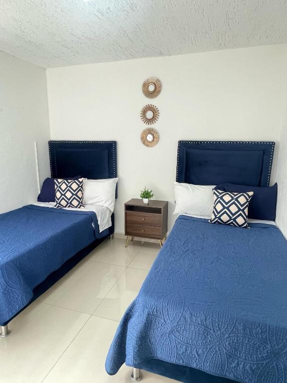 a bedroom with two beds and a clock on the wall at Suite Jacarandas 103 in Guadalajara