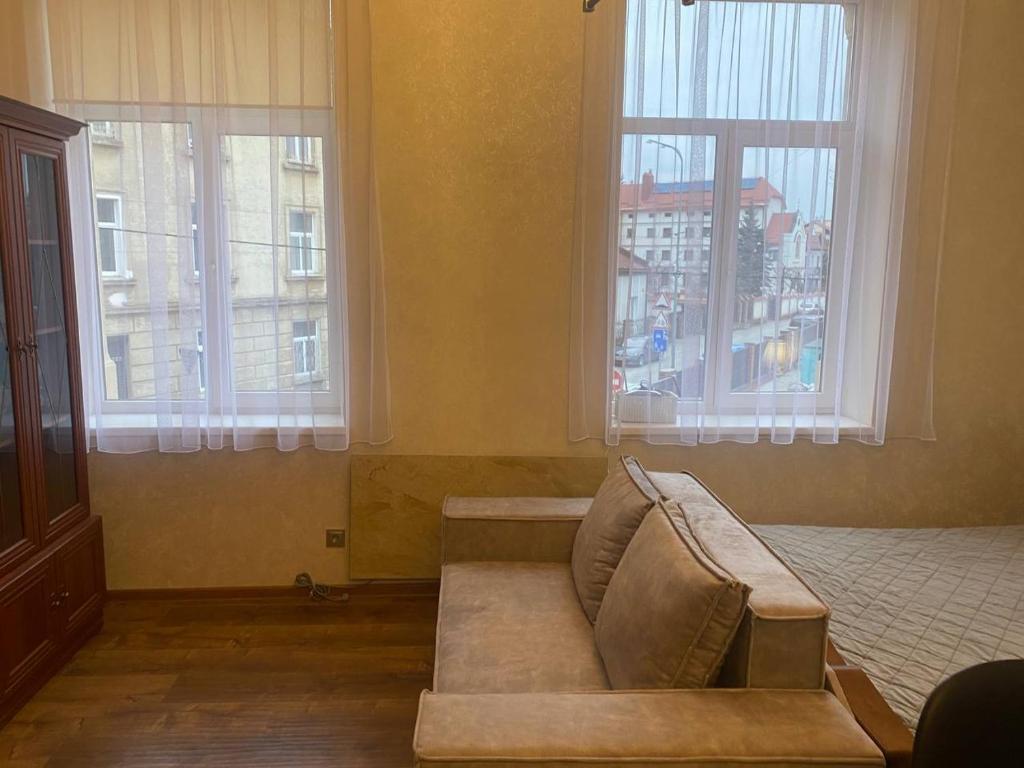 een woonkamer met een bank en 2 ramen bij Апартаменти на вулиці Залізняка - бічна вулиці Антоновича in Lviv